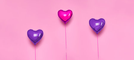 Set of Air Balloons. Bunch of pink color heart shaped foil balloons isolated on pink background. love. Celebrations. Valentine's Day party decorations. Metallic red Heart air balloonsの写真素材
