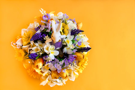 Easter decoration with beautiful spring flowers in box, Easter eggs and bunny on yellow background. Festive concept with copy space.の写真素材