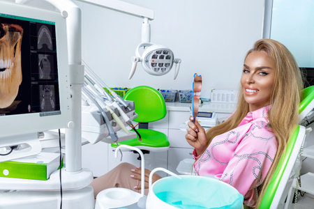 Beautiful happy woman sitting in the dental chair and enjoying her new smile. Porcelain veneers. Teeth whitening.の写真素材