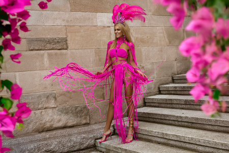 Sexy blonde goddess with long legs in sexy pink macrame dress sensually walks around the city.の写真素材