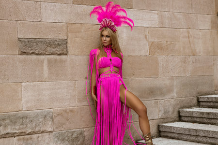 Sexy blonde model with long legs in sexy pink macrame dress sensually walks around the city.