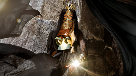 Majestic Woman in Black and Gold Royal Costume With Crown and Mask in Tropical Mauritius Resort, Palm Trees, Sunny Luxury Fashion Portraitの写真素材