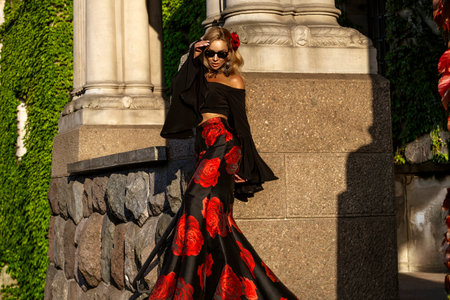 Flamenco style woman in dramatic black and red rose print gown posing in garden of palaceの写真素材