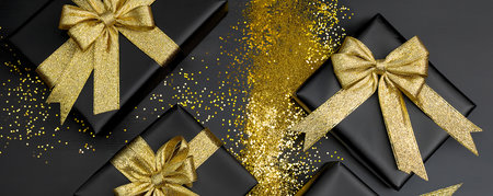 Luxurious Black Christmas Gifts with Gold Bows and Golden Glitter on Black Background