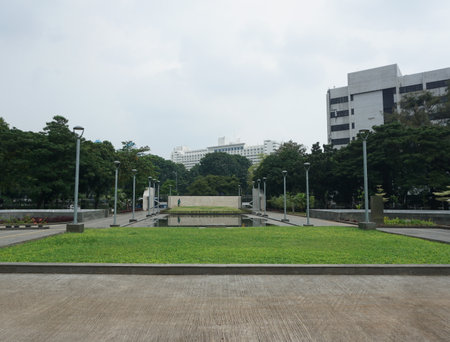 The view of the attendant watering the garden yard. This park is surrounded by greenery and several pillars of daytime garden lights in indonesiaの写真素材