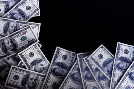 Chaotic scattered hundred dollars on a dark background.の写真素材