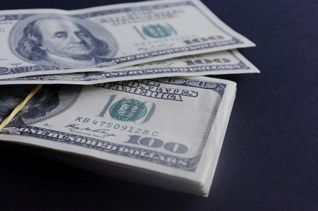 Close up stack of hundred dollar baknotes on a dark background.