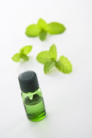 bottle of oil and fresh mint isolated on whiteの写真素材