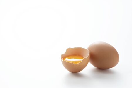 A broken egg placed on a white background with copy space was photographed from an angle.