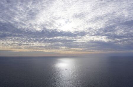 The vast ocean and small fishing boats at duskの写真素材