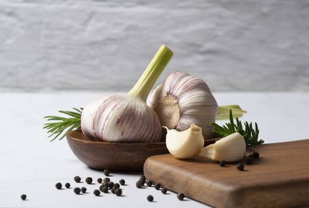 Fresh garlic, herbs and spices set on a marble table. Image of cooking with garlic.