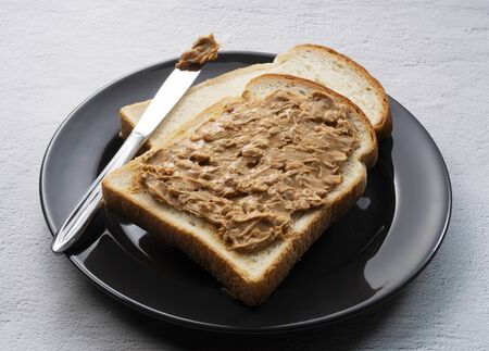 Close-up of peanut buttered bread set against a stone background