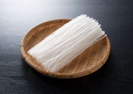 glass noodles in a colander on a black backgroundの写真素材