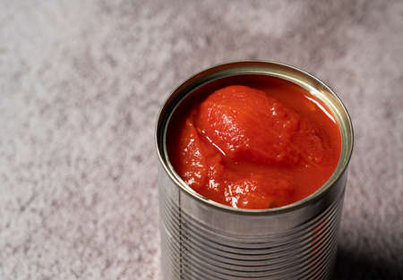 Whole tomato cans on a stone backgroundの写真素材