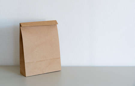 A brown paper bag placed in front of a white wall with space.の写真素材