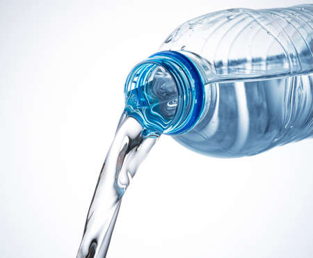 Close up of water coming out of a plastic bottle on a white backgroundの写真素材