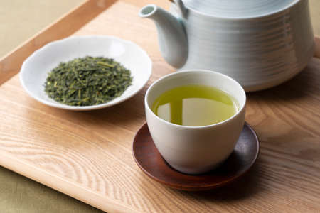 Green tea and tea leaves placed on a wooden tray. Japanese green tea imageの写真素材