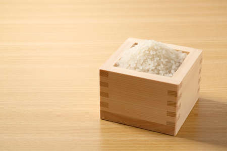 A closeup of rice in a Japanese measure cup in a wooden backgroundの写真素材