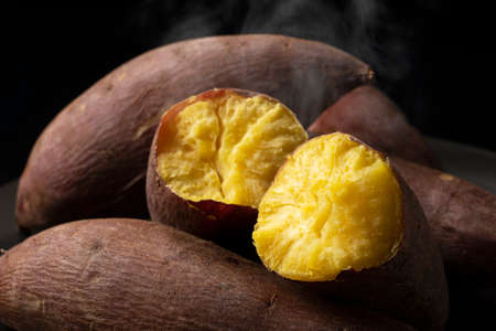 A steaming sweet potato split in half on a black backgroundの写真素材