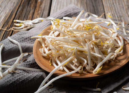 Bean sprouts and cloth in a wooden plate set against an old wooden backgroundの写真素材