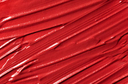 Red lipstick smudged background. Lipstick or other makeup product swatch. Acrylic paint smeared...
