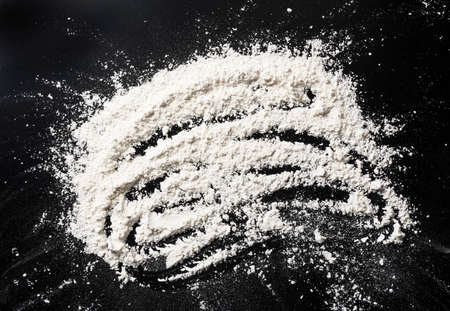 White flour smeared on black table, dough ingredients, top viewの写真素材