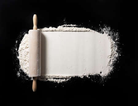 Bake background with free space for text. Roll the pins and flour on the black table. Top viewの写真素材