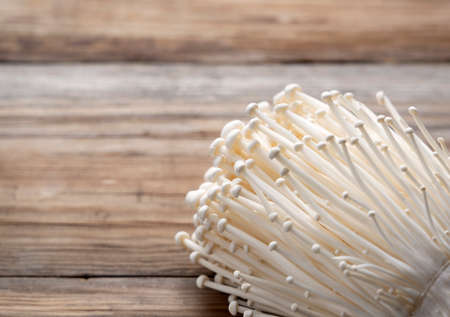 Enoki mushrooms placed on a wooden background. Close-up, image of mushrooms.の写真素材