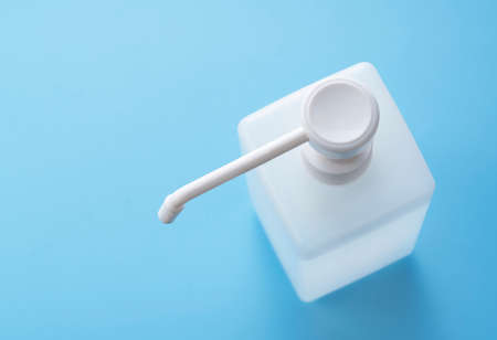 Bottle of alcohol sanitizer spray placed on a blue background in copy space. Image of sanitizing and...