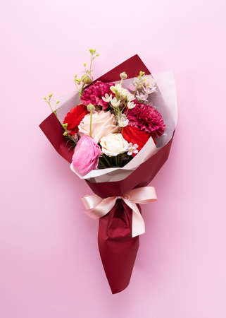 A bouquet of flowers placed on a pink background. Viewed from directly above.