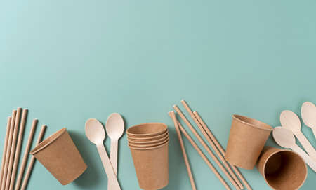 Disposable paper cups, straws, and spoons set against a pastel green background. The zero-waste concept. View from above.の写真素材