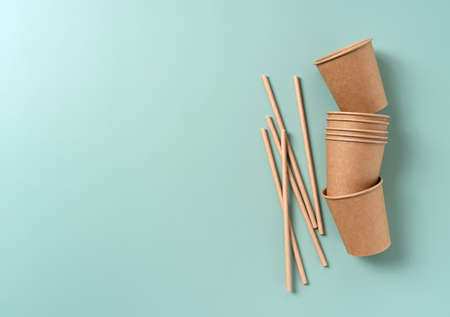 Disposable paper cups and straws set against a pastel green background. Zero-waste concept. View from above.の写真素材