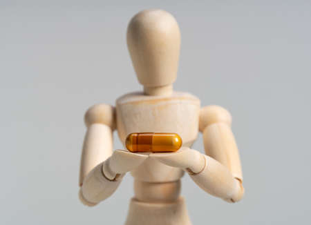 Wooden mannequin with pills on white background.  Concept of pharmaceuticals and supplements.の写真素材