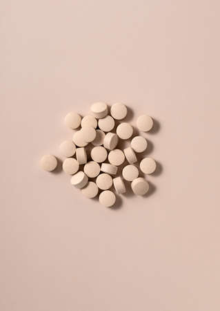 Beige pills on a beige background. Concept of pharmaceuticals and supplements. View from above.の写真素材