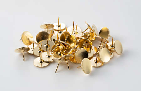 Golden thumbtacks placed on a white background