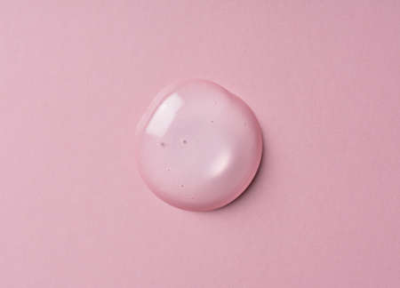 Transparent gel drop on pink background. Liquid gel texture. Beauty serum drop. Transparent skin care product sample.の写真素材