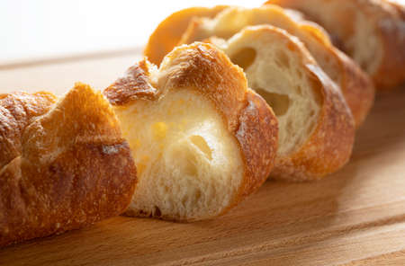 A sliced baguette placed on a cutting board. French bread with elongated shape.