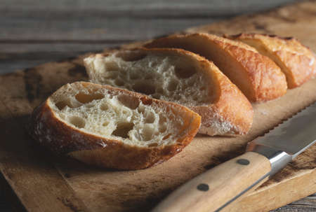 A sliced baguette on an old wooden cutting board. Close-up.の写真素材