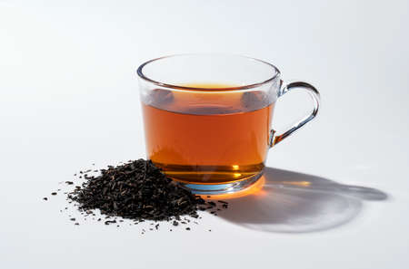 Hot tea and tea leaves in a glass on a white backgroundの写真素材