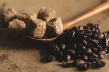 Brown cane sugar cubes and coffee beans on a wooden background. Retro, vintage style.の写真素材