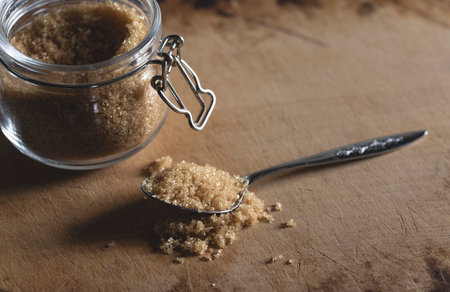 Brown sugar and spoon in a glass container set against an old wooden background. Text space.の写真素材