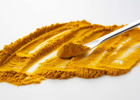Silver spice spoons with dry turmeric powder on a white background. Curcuma domestica powder.の写真素材