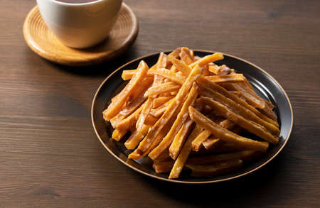 Imokempi placed on a wooden background. Imokempi is a Japanese sweet made from sweet potatoes that are fried and coated with sugar.の写真素材