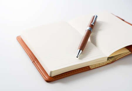 Leather notebook and pen placed against a white background. Business image.の写真素材