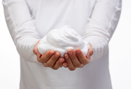 Female holding soap bubbles on white background. Hands with white bubbles. Texture of white soap foam on female hand.の写真素材