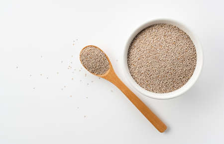 White chia seeds and wooden spoon in white bowl set against white background. View from directly above.の写真素材