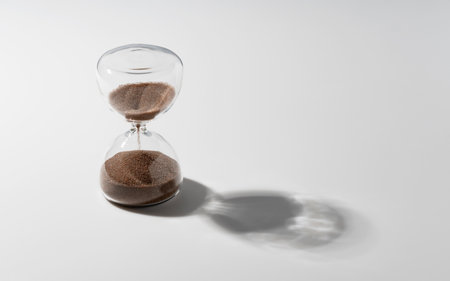 An hourglass of brown sand set against a white background.