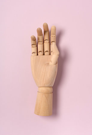 Wooden mannequin hands placed on pink background. View from directly above.の写真素材