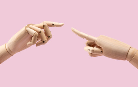 Two wooden mannequin hands on pink background. Fingers together. Business concept.の写真素材