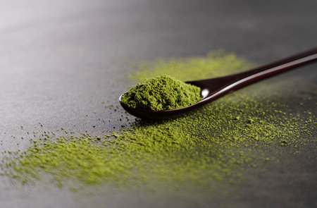 Matcha and wooden spoon on black background. Matcha powder.の写真素材